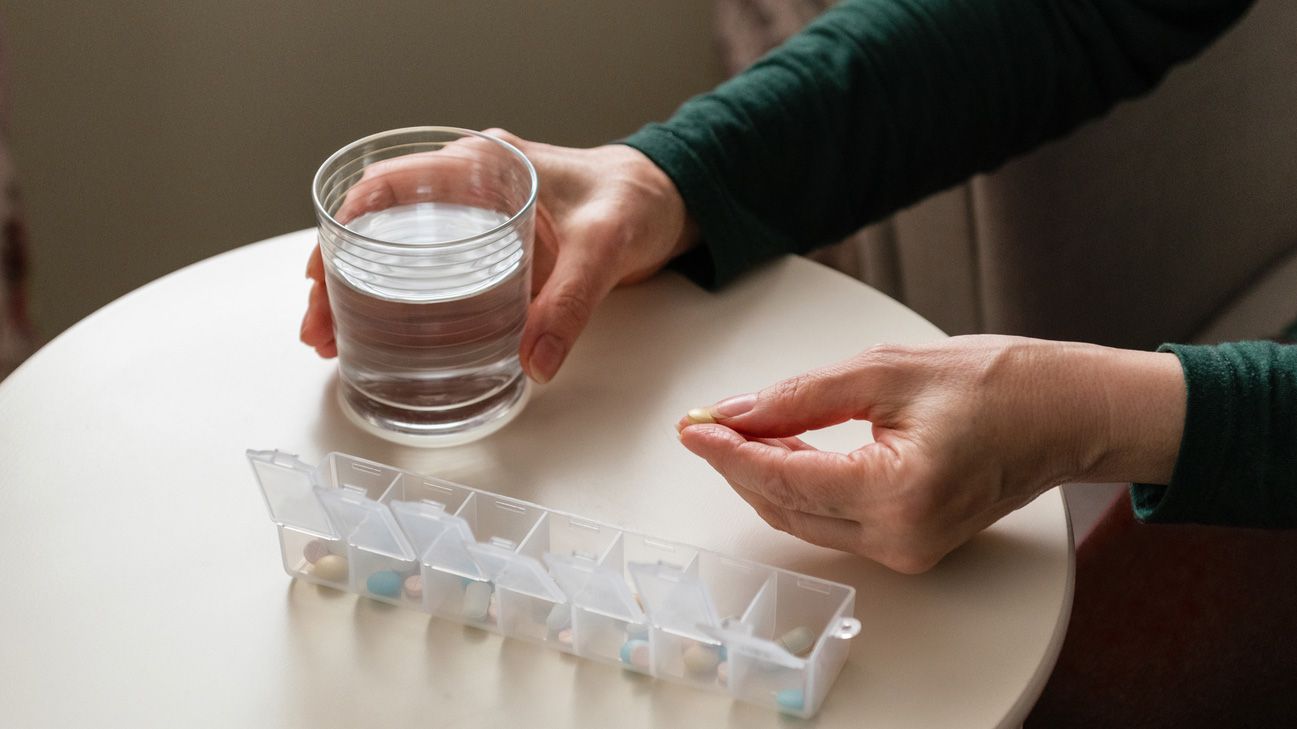 A person taking a multivitamin with water.