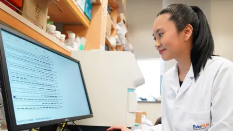 Duke-NUS Medical School Prof Anissa Widjaja wearing a lab coat and analysing the experimental data