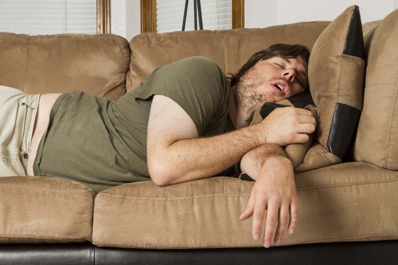 Guy sleeping on the couch in what looks like an uncomfortable position; Shutterstock ID 241260808; purchase_order: -; job: -; client: -; other: -