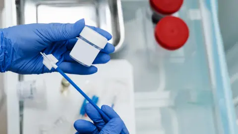 Getty Images Gynaecologist is holding flask for cytology Pap smear test in hands. 