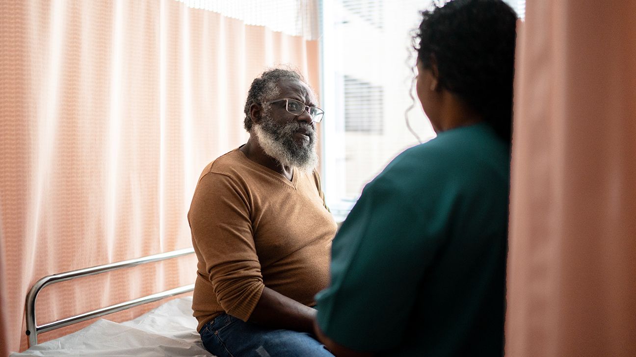 Man with beard talks to a physician.