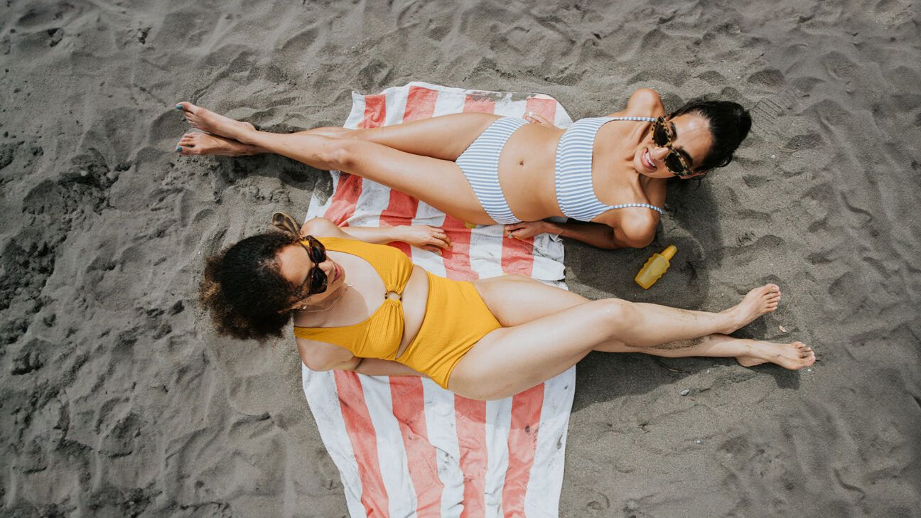 Two females tanning on the beach.