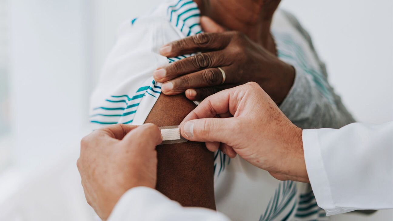 A person placing a bandaid on another person's arm.