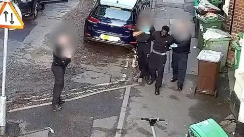 Nottinghamshire Police A CCTV image of Valdo Calocane being arrested on a street in Nottingham by three officers, whose faces are blurred in the image