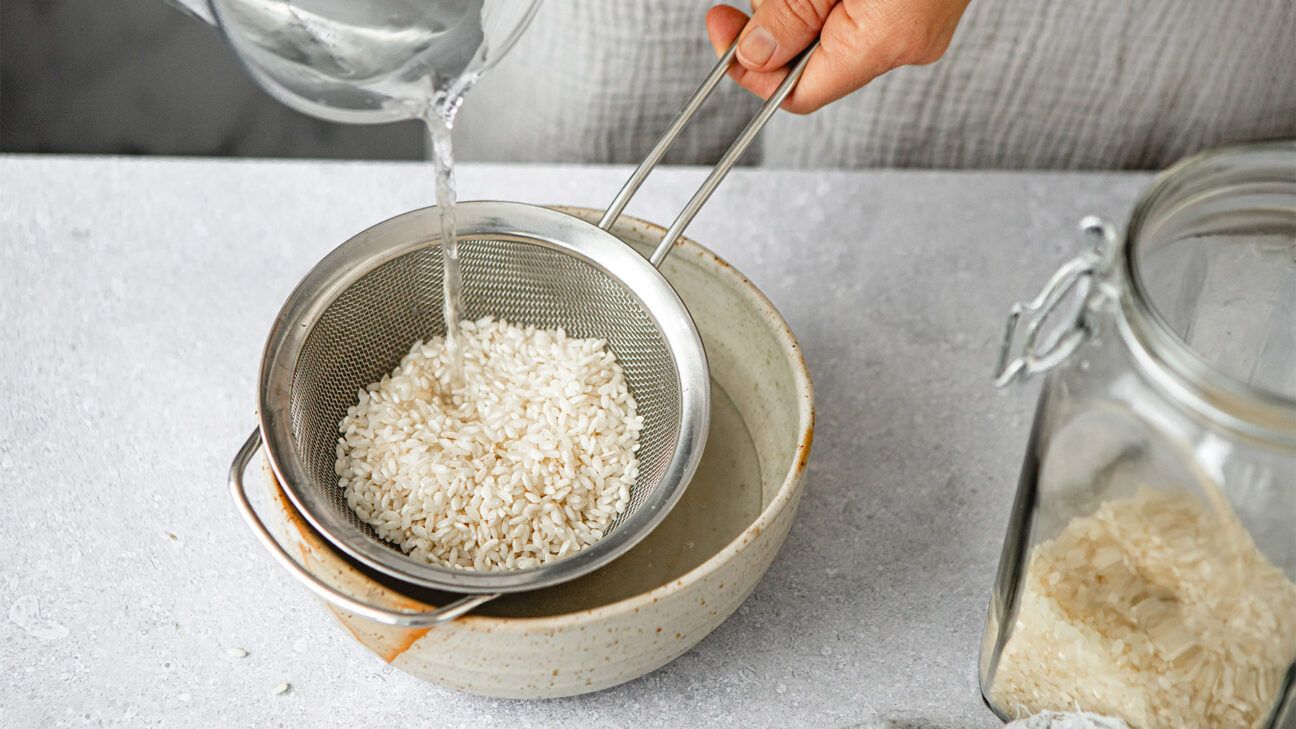 Water being poured over rice in a strainer.