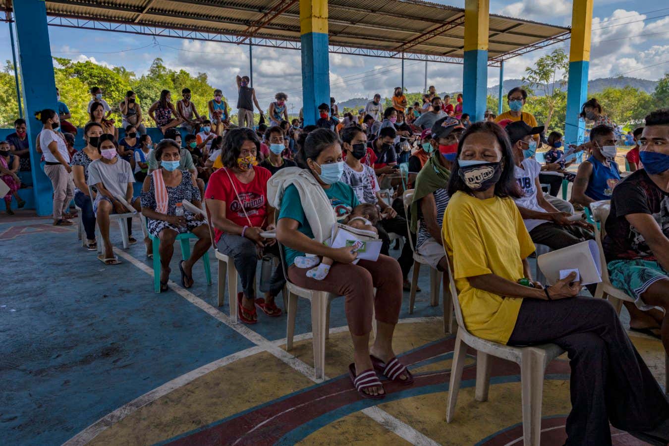 ARINGAY, PHILIPPINES - DECEMBER 01: Residents queue to receive a dose of Pfizer BioNTech COVID-19 vaccine at a rural village on December 01, 2021 in Aringay, La Union province, Philippines. The Philippines is rushing to vaccinate its population as it mulls making COVID-19 vaccination mandatory and amid the looming threat of the Omicron variant of the coronavirus. The country, which has just approved booster shots for its adult population, launched a three-day national vaccination holiday on November 29 to December 1 with the goal of vaccinating at least nine million additional people. (Photo by Ezra Acayan/Getty Images)