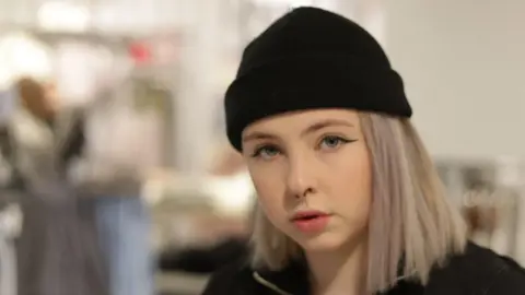 BBC Marina Waldron wearing a black hat. She has blonde hair and is looking directly at the camera