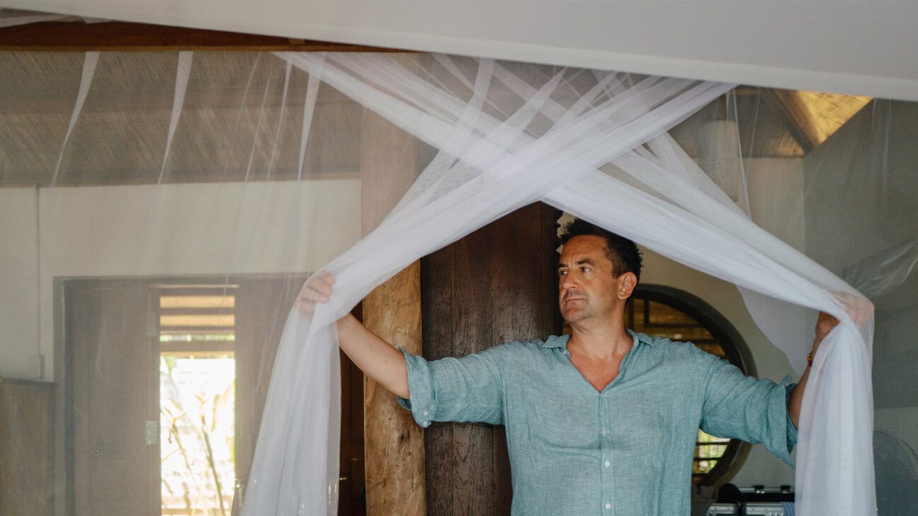 A man opening a mosquito net.