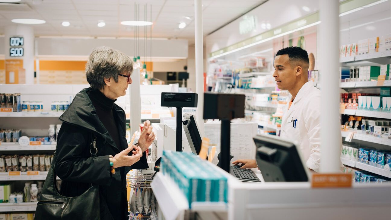 An older female paying for prescription drugs at a pharmacy.