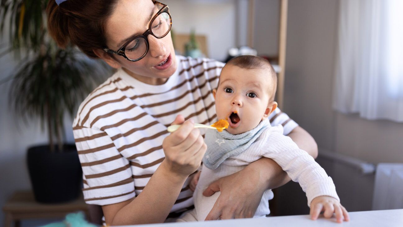 Female caregiver feeding an infant with a spoon