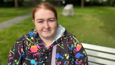 Jo Adnitt/BBC Leah sitting on a park bench 