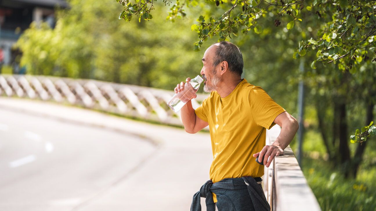 Older male stops on side of road to drink water