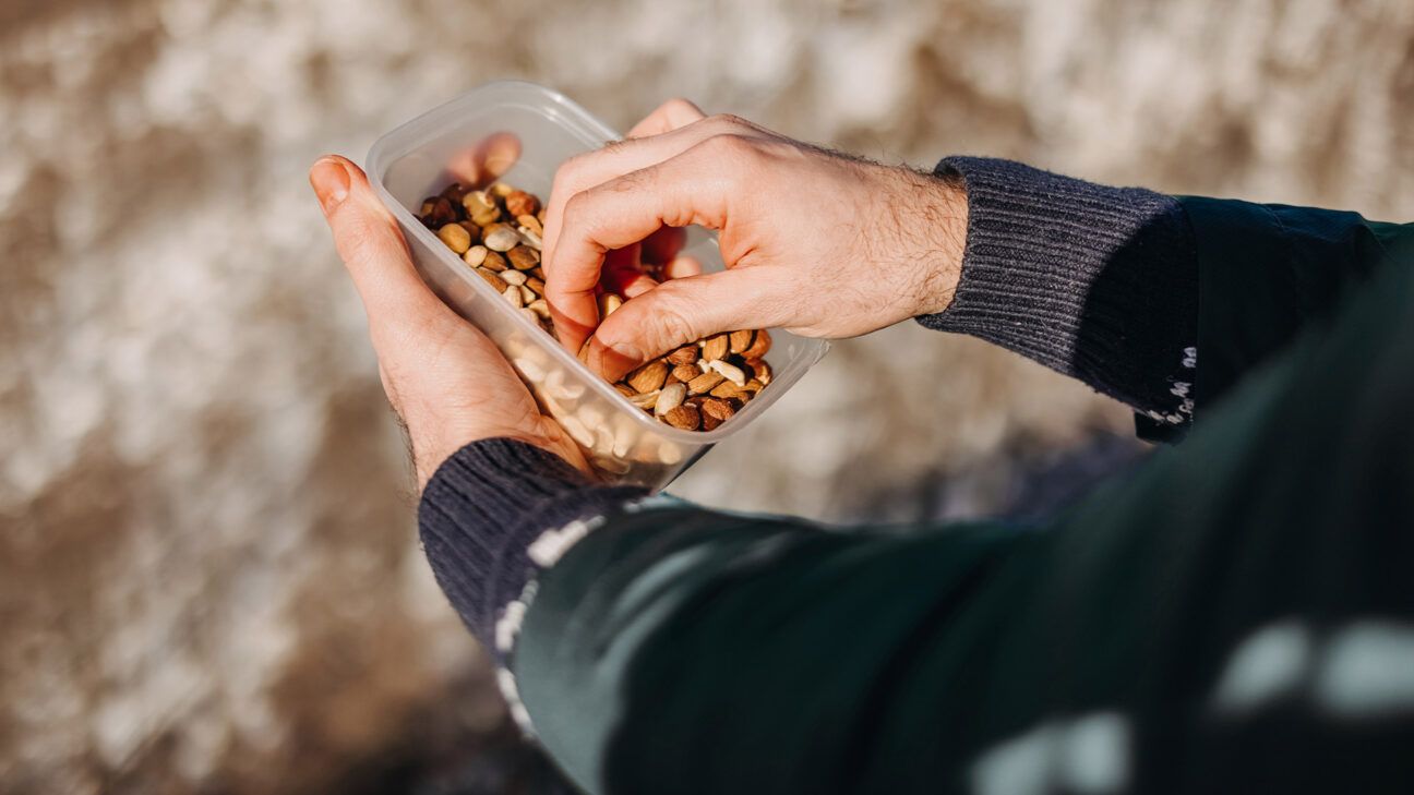 Person eats nuts from a container