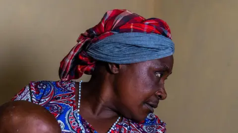 Glody Murhabazi Beatrice Kachera holds a young child  in Lwiro hospital, DR Congo