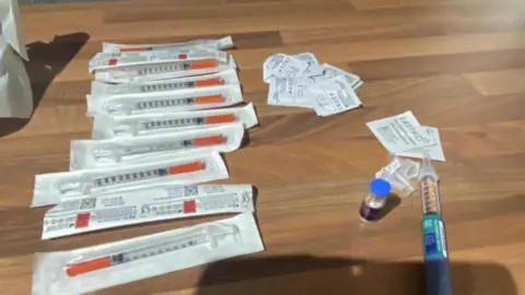 The fraudulent pens that Michelle Sword bought. They are laid out on a wooden table.