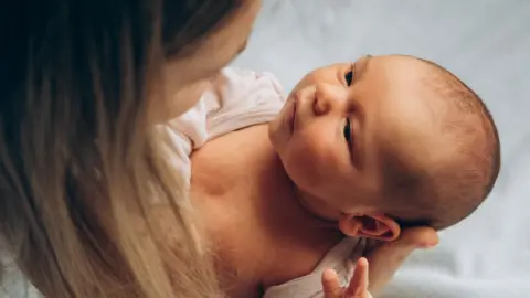 Getty Images Mother holding a newborn baby and looking into the baby's eyes