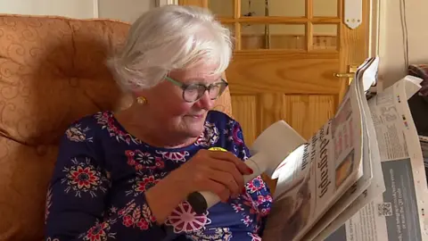 BBC Pam Maxwell using a reading device with her newspaper because she has eyesight deterioration