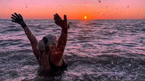 Jessie Hallett Woman in the sea with sunset