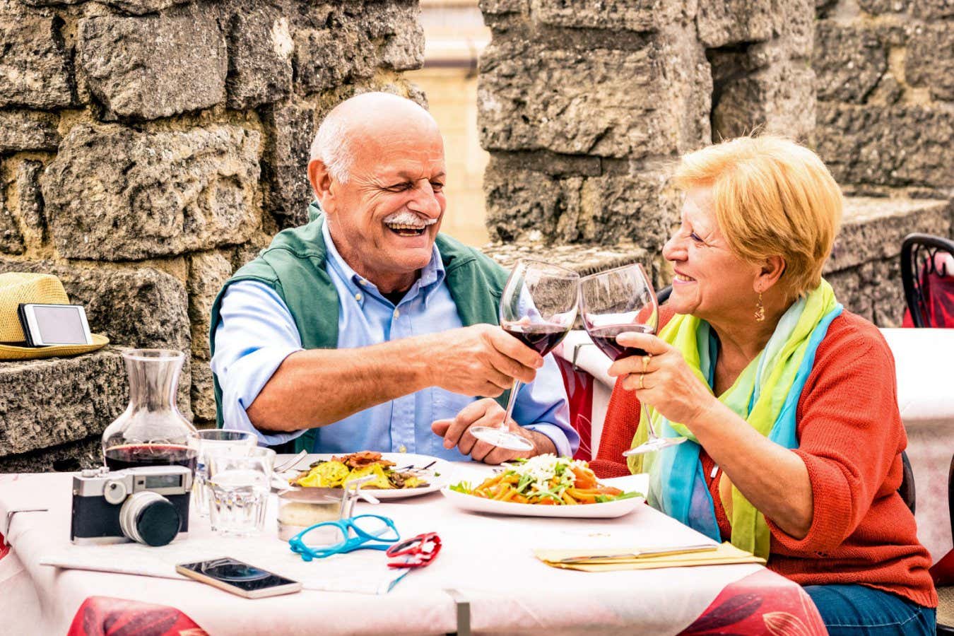 2FNMAE7 Senior couple having fun and eating at restaurant during travel - Mature man and woman wife in old city town bar during active elderly vacation