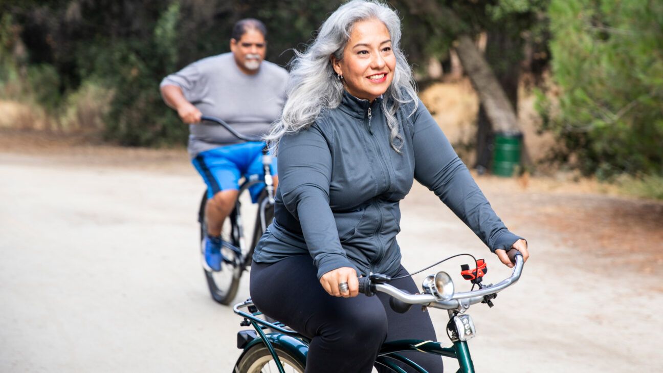 An older female and male riding bicycles.