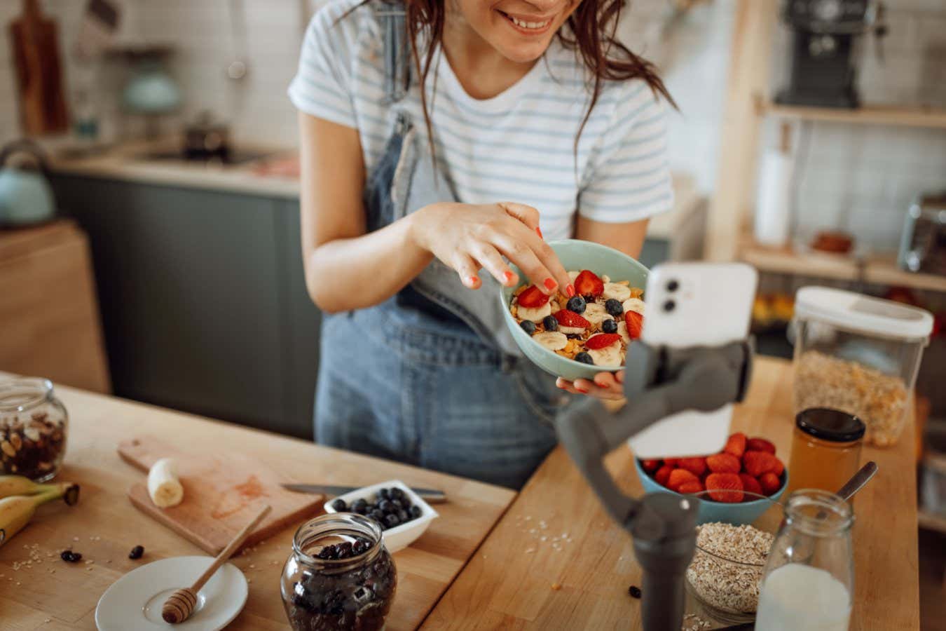 Beautiful cheerful woman vlogging from her domestic kitchen