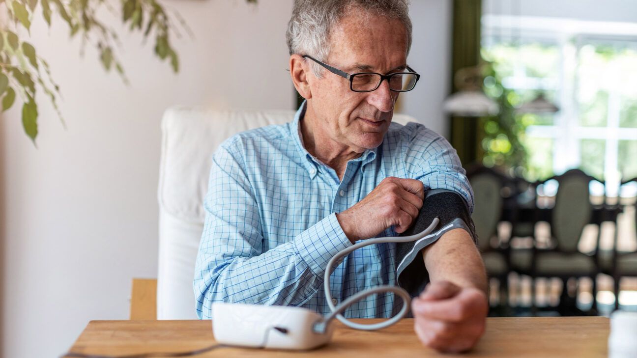 Older male checking blood pressure at home