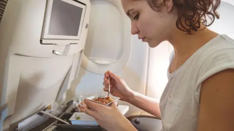 Getty Images Woman eating on a plane