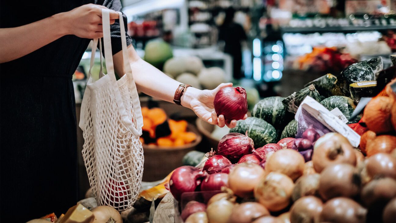 A person buying onions in a store.