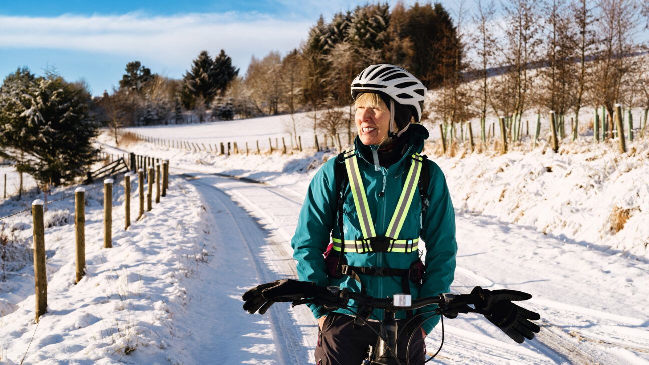 A female riding a bike on a snowy road.