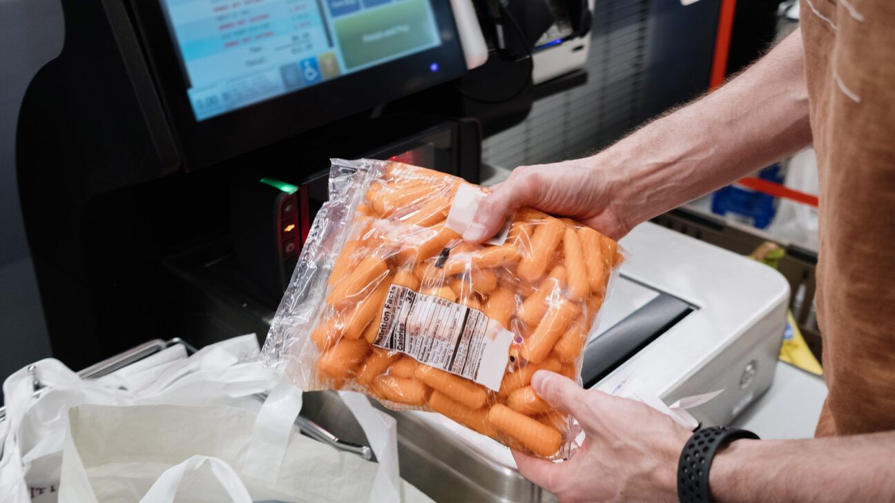 A person buying a bag of baby carrots.