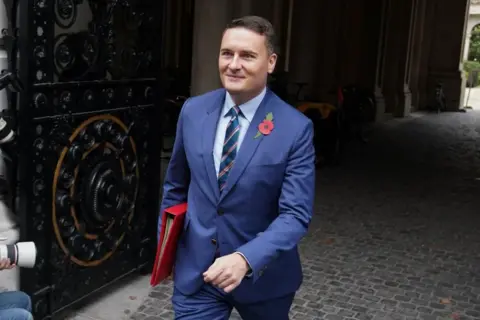 PA Wes Streeting in a suit, smiling, wearing a poppy