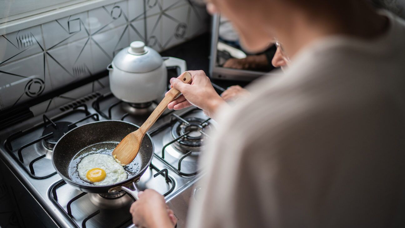 A person frying an egg. 