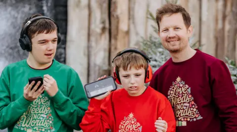 John Thompson Jude (left) wears a green jumper, Tommy (centre) wears a red jumper and James (right wears a maroon jumper, all Christmas themed