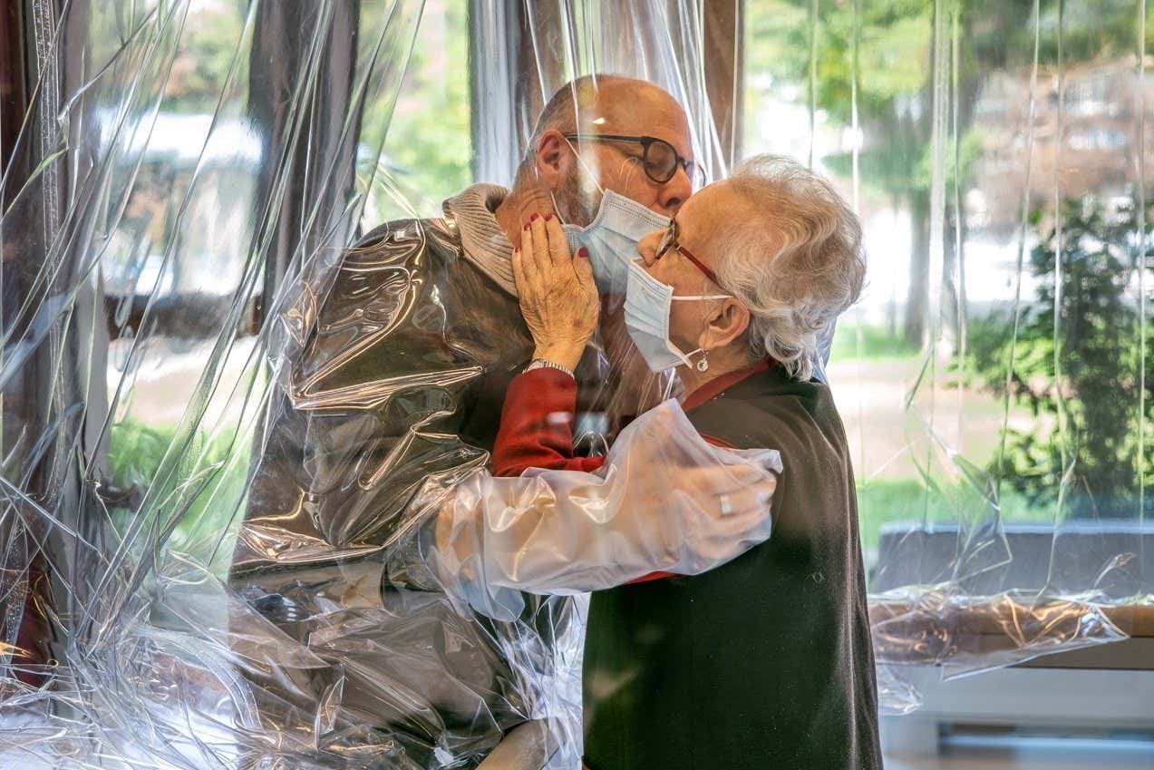 A care home resident kisses a relative through a plastic sheet at a care home in Castelfranco Veneto, Italy, in November 2020