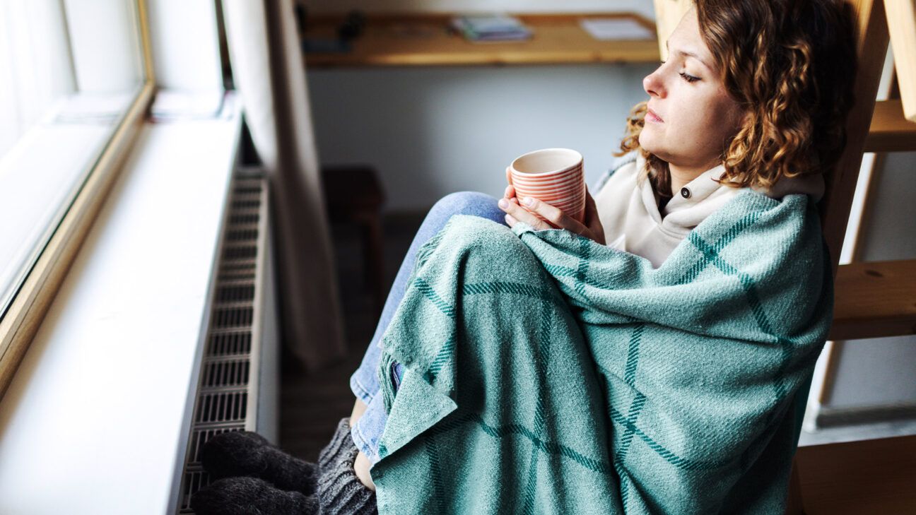 Female wrapped in blanket drinking tea