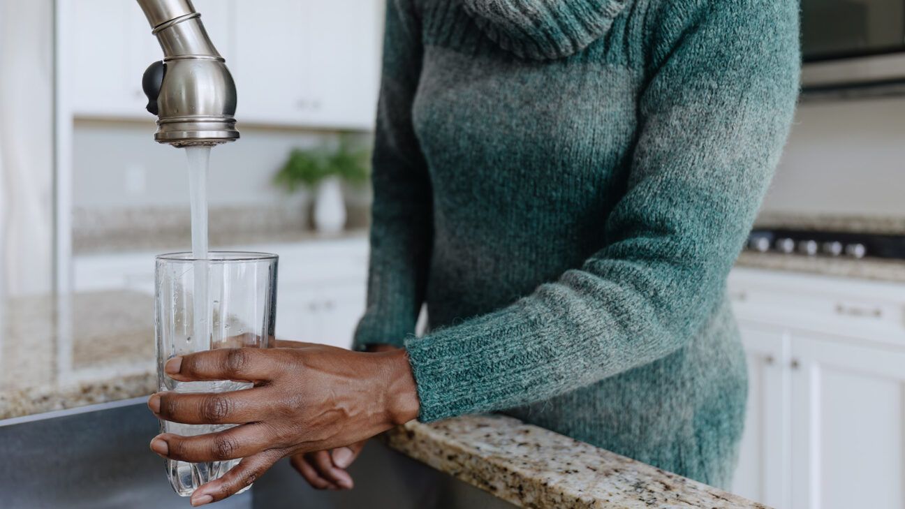 Female filling a glass with tap water in kitchen