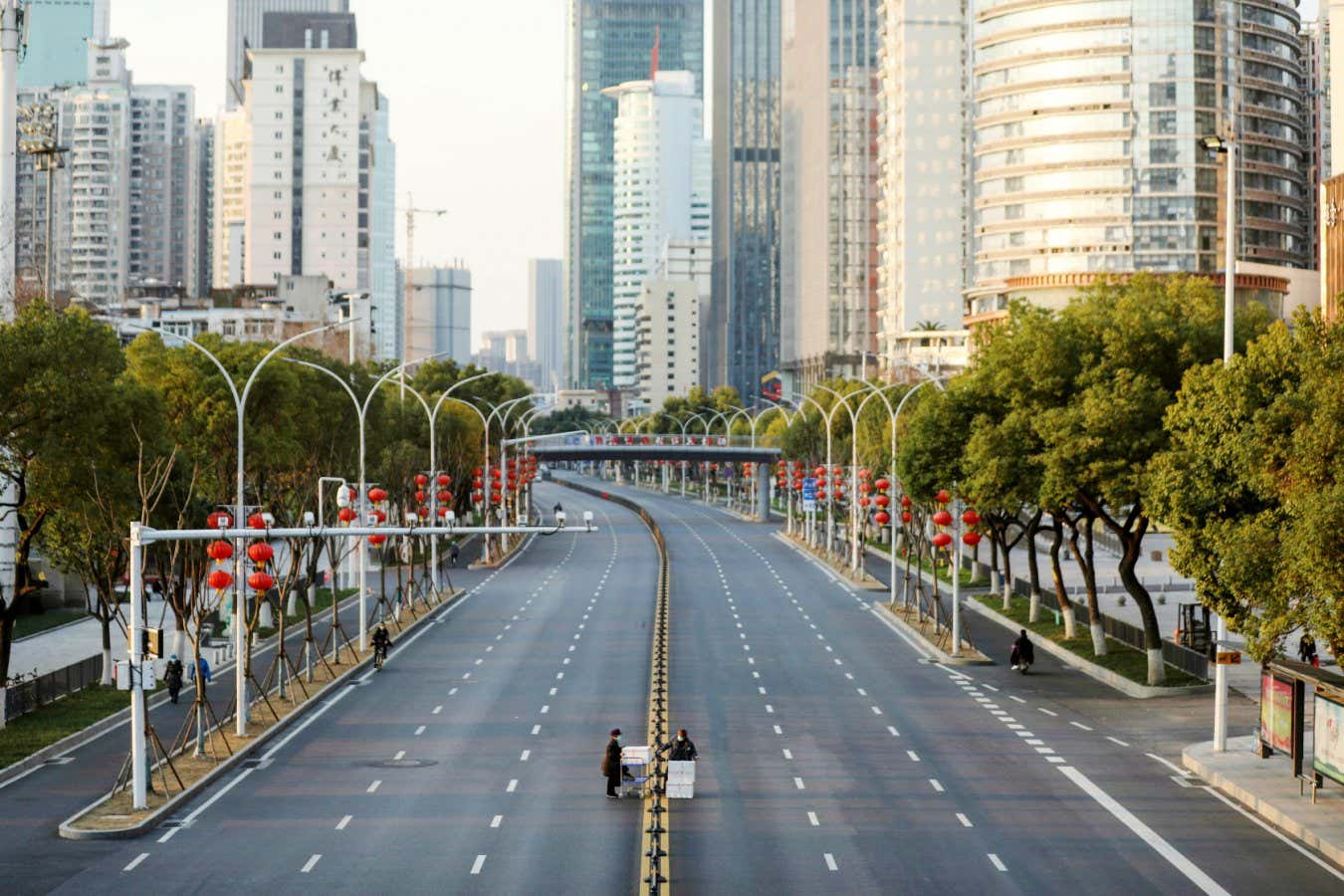 2NR8F5N Two workers try to get boxes of vegetables over the barriers in the empty road outside the Union Hospital in Wuhan in central China's Hubei province Thursday, Feb. 20, 2020. The city badly-hit by the COVID-19 escalated its ban on vehicles in the outbreak. (FeatureChina via AP Images)