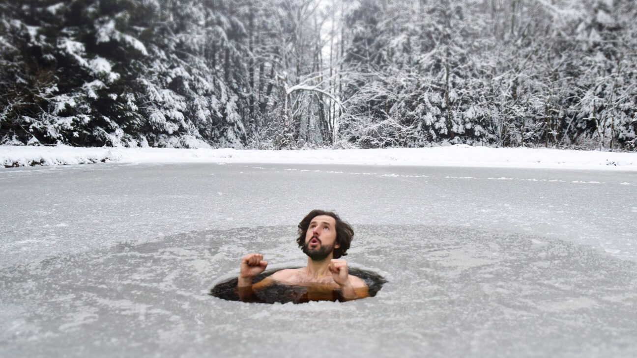 Male takes cold plunge in icy lake outdoors