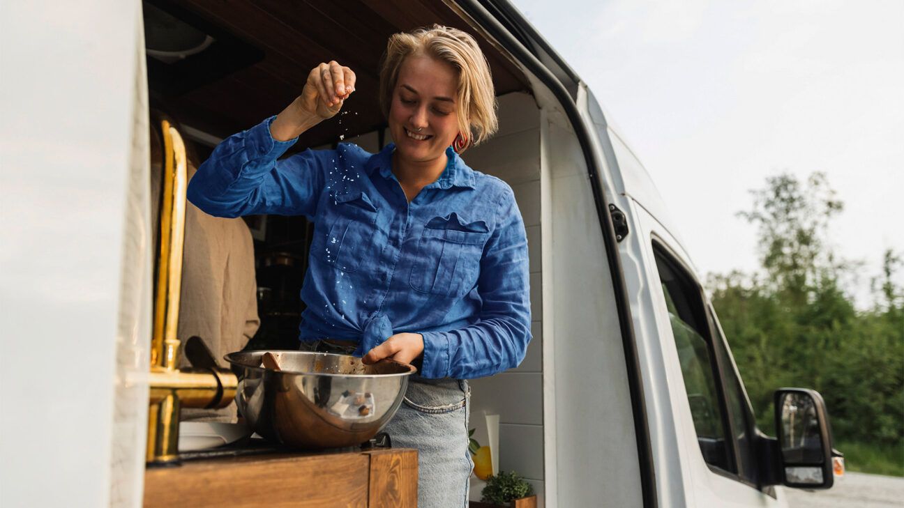 Female chef salts food in a van