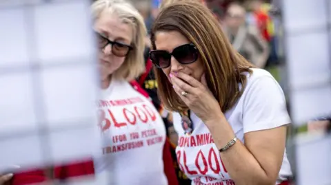 Getty Images Two women stand outside the building in Westminster where the final report into the infected blood inquiry was published in May 2020. They are both wearing white T-shirts with the slogan 'Contaminated Blood