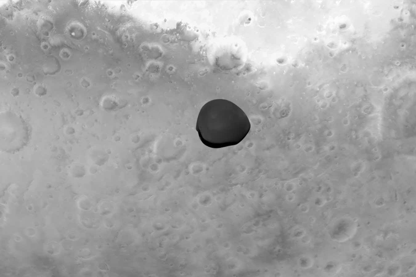 Deimos appears dark, framed by Mars