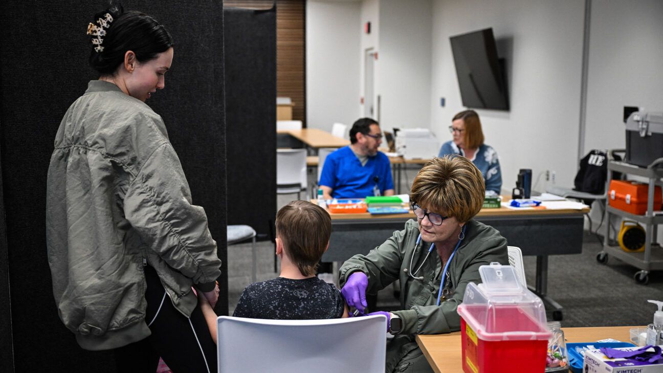 A child is immunized against measles with their caregiver