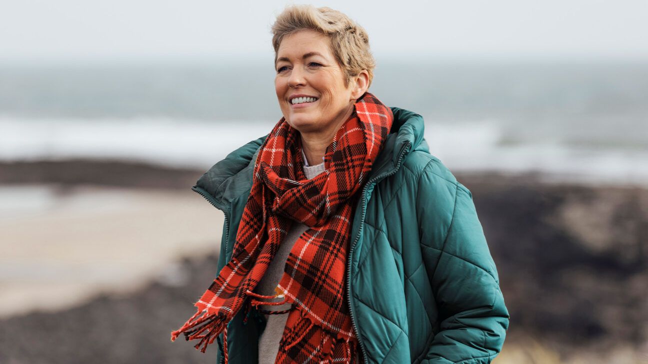 Female wearing scarf walking by the ocean