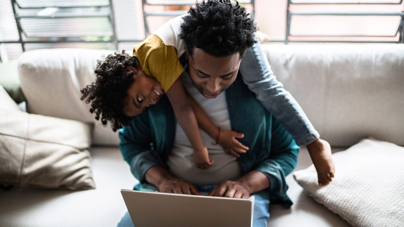 Father and young son with laptop on couch