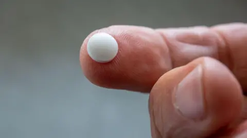 Getty Images Close-up of white pill on a finger-tip