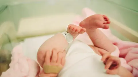 Getty Images A newborn baby in a hospital ward - all you can see are the baby's feet and a security tag