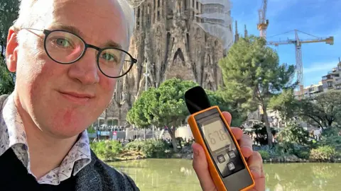 BBC James Gallagher holding a sound meter 