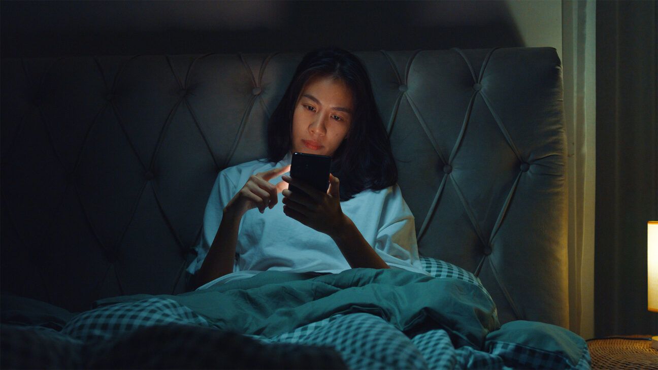 Female in bed using smartphone