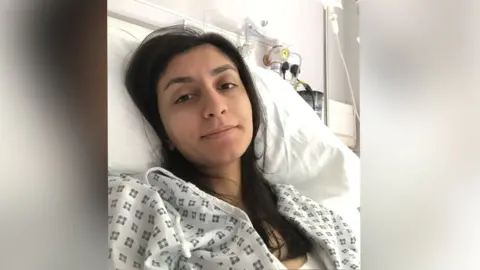 Roya Rasouli Roya Rasouli is in a hospital bed and is wearing a white hospital gown following surgery.
