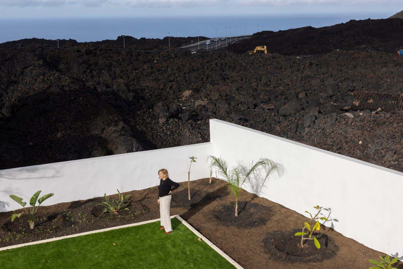 Jonathan Browning, La Palma Series Canu Martin-Mur, (67) from Spain. She had to remove some lava that broke her garden walls and destroyed mature palm trees. She has since replaced tha wall and laid down an artificial lawn and planted new palms and plants to regrow again. La Palma. An island of the Canaries. Two years after the Cumbre Vieja volcanic eruption in late 2021. Photography taken on January 2024.